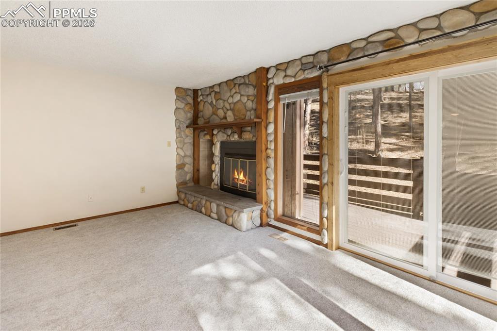Image 4 of 27: The walkout living room with carpet flooring, a fireplace with stone accent