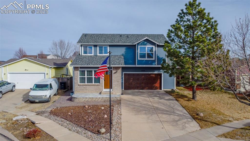 Caption: View of front of house featuring a garage, concrete driveway, and brick siding