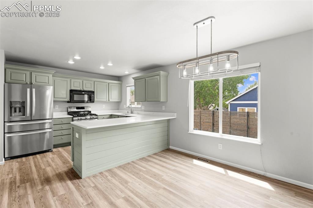 Image 10 of 30: Kitchen with appliances with stainless steel finishes, light countertops, a