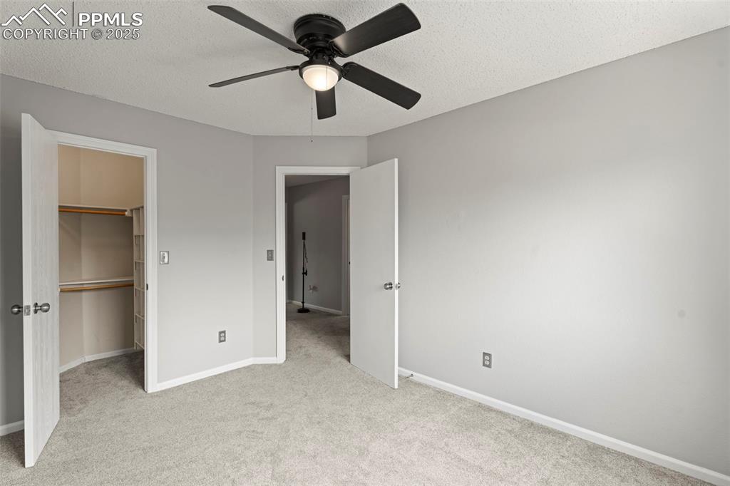 Image 16 of 30: Unfurnished bedroom with a textured ceiling, a spacious closet, light carpe