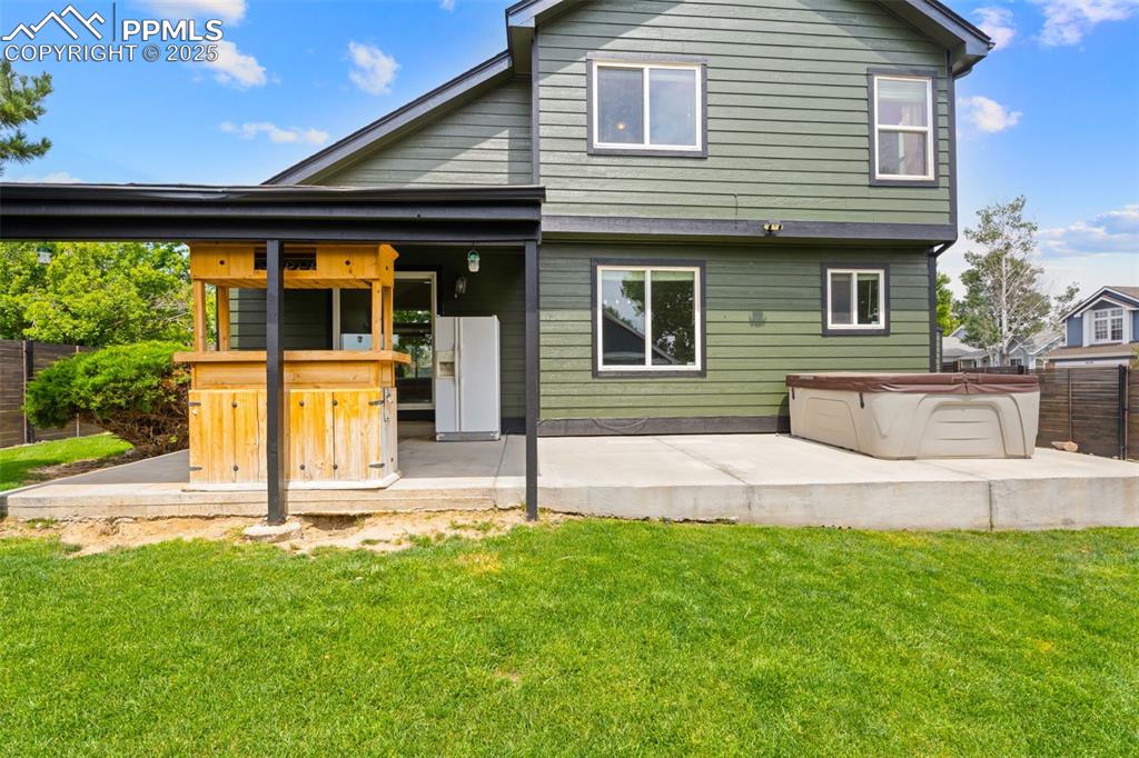Image 23 of 30: Rear view of house featuring a hot tub and a patio area