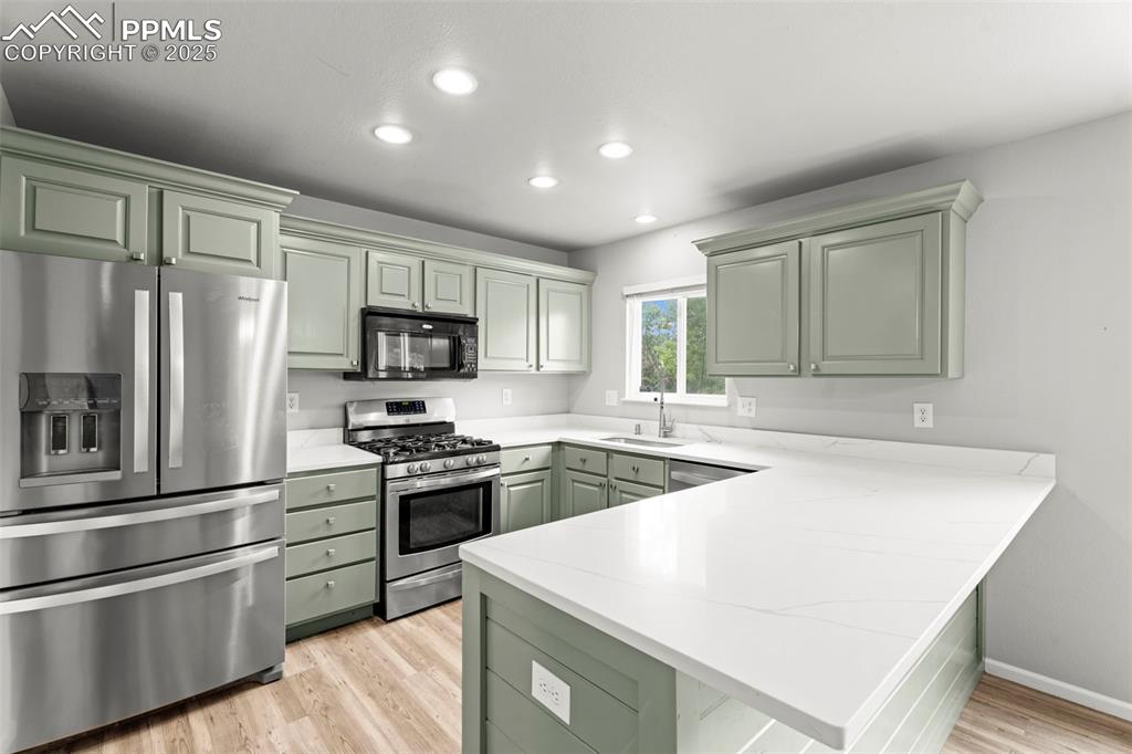 Image 4 of 30: Kitchen with appliances with stainless steel finishes, a peninsula, light w