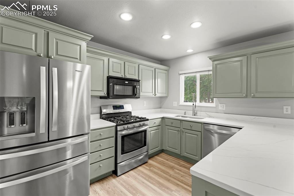 Image 5 of 30: Kitchen with stainless steel appliances, light wood finished floors, recess
