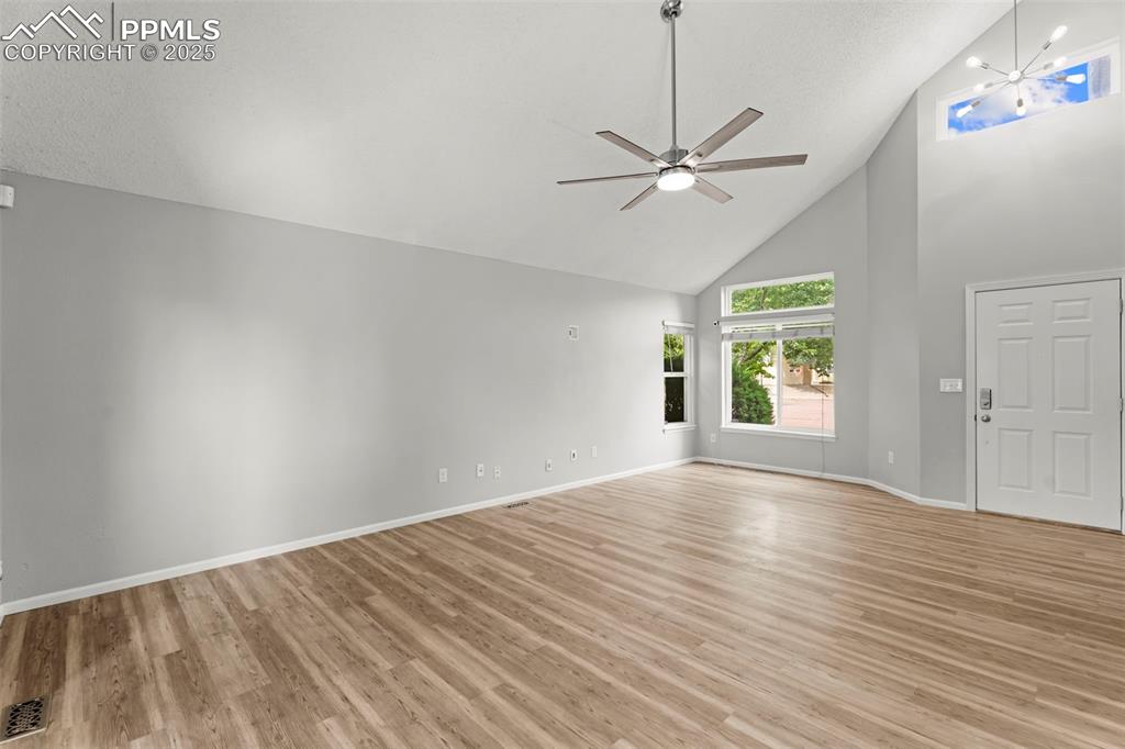 Image 9 of 30: Unfurnished living room featuring high vaulted ceiling, light wood-type flo