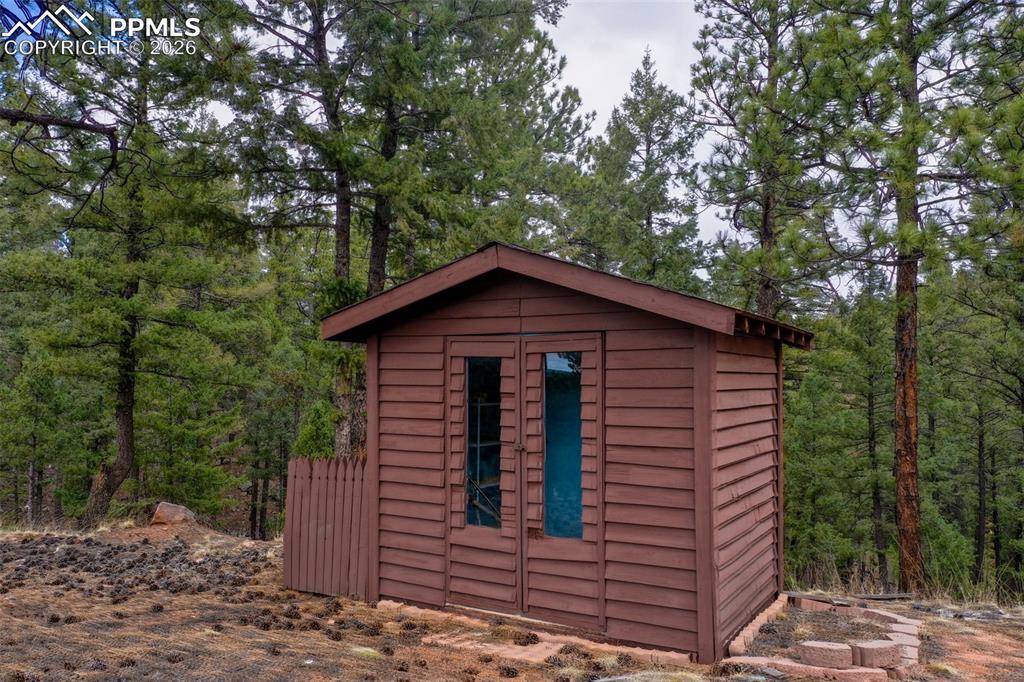 Image 29 of 30: Wood-sided outbuilding featuring double doors with glass lites and a sloped