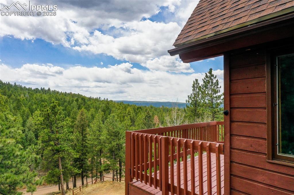 Image 30 of 30: Wood-sided exterior with a sloped shingle roof and an attached wooden deck