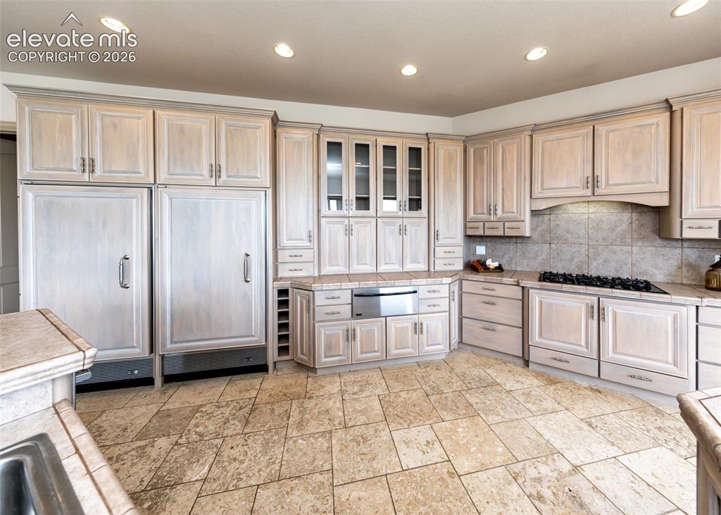 Image 10 of 50: Kitchen featuring light wood cabinetry, stone tile flooring, a built-in gas