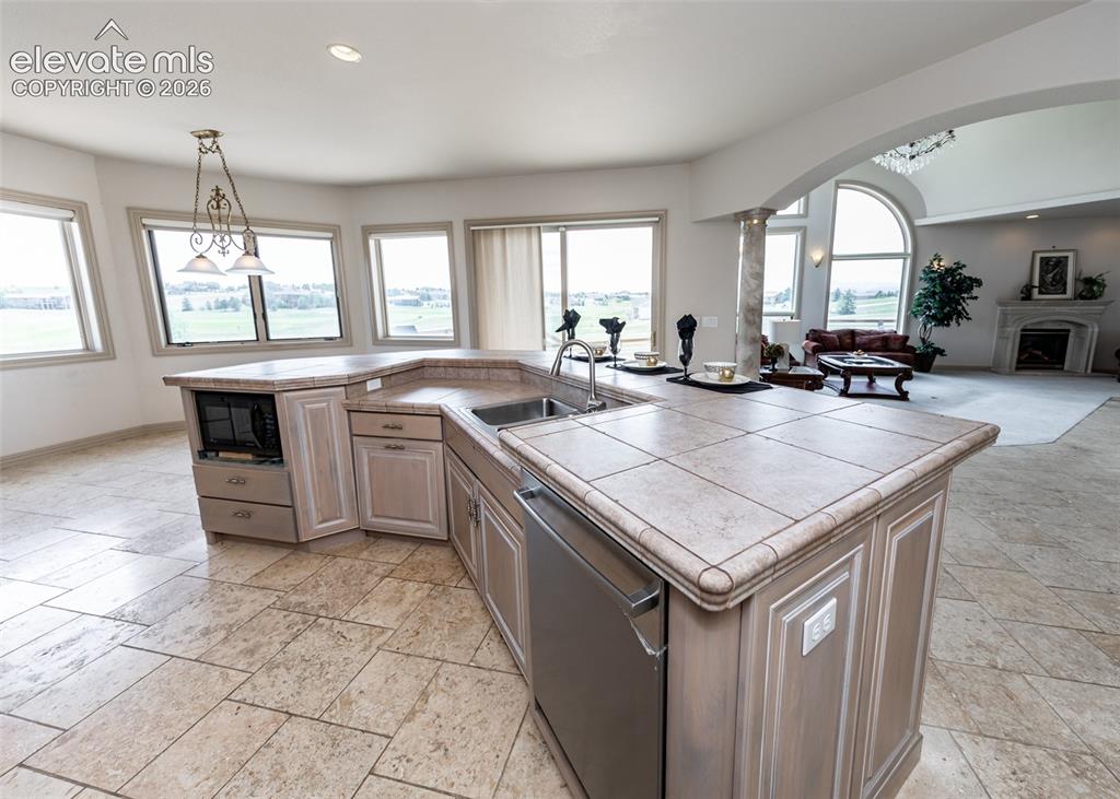 Image 14 of 50: Expansive kitchen island featuring tile countertops, integrated sink, and s