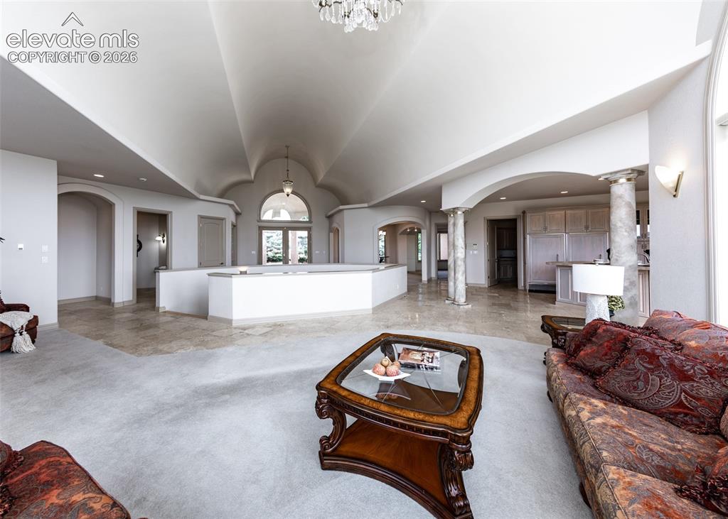 Image 16 of 50: Spacious interior featuring a vaulted ceiling with a central chandelier