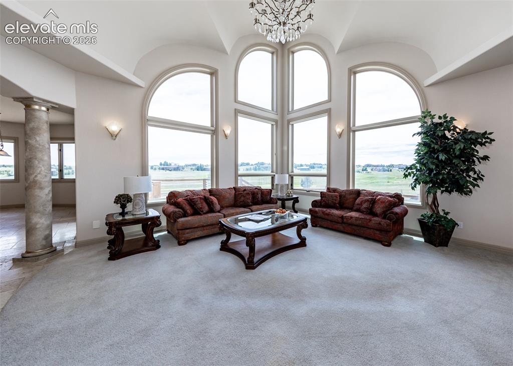 Image 17 of 50: Grand living area featuring a vaulted ceiling and an ornate chandelier