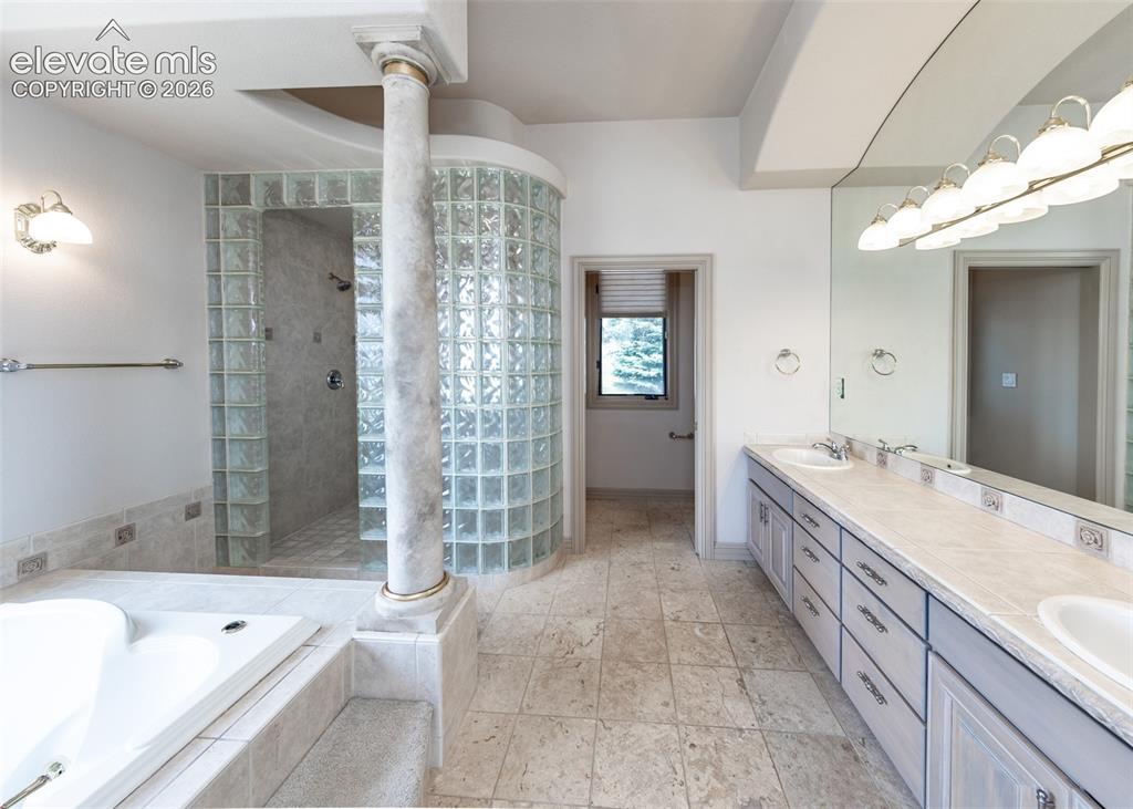 Image 24 of 50: Spacious bathroom with a glass block shower enclosure, large built-in soaki