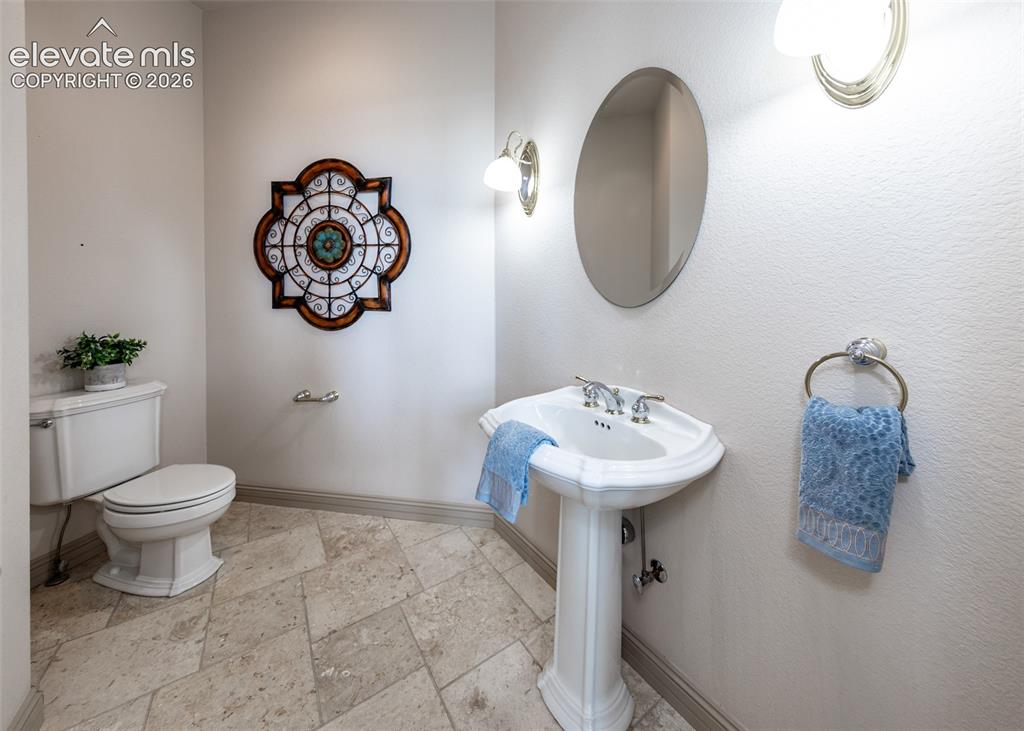 Image 25 of 50: Pedestal sink with chrome fixtures and an oval mirror, complemented by ston