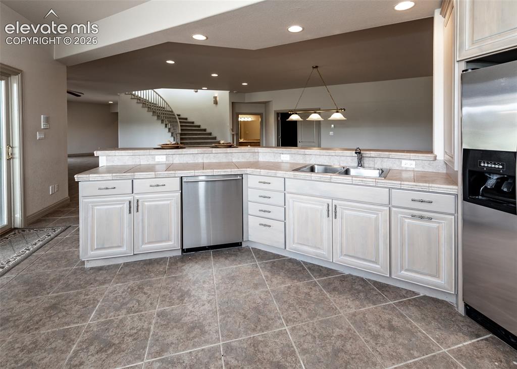 Image 34 of 50: Kitchen featuring tile flooring, light wood-finish cabinetry, tile countert