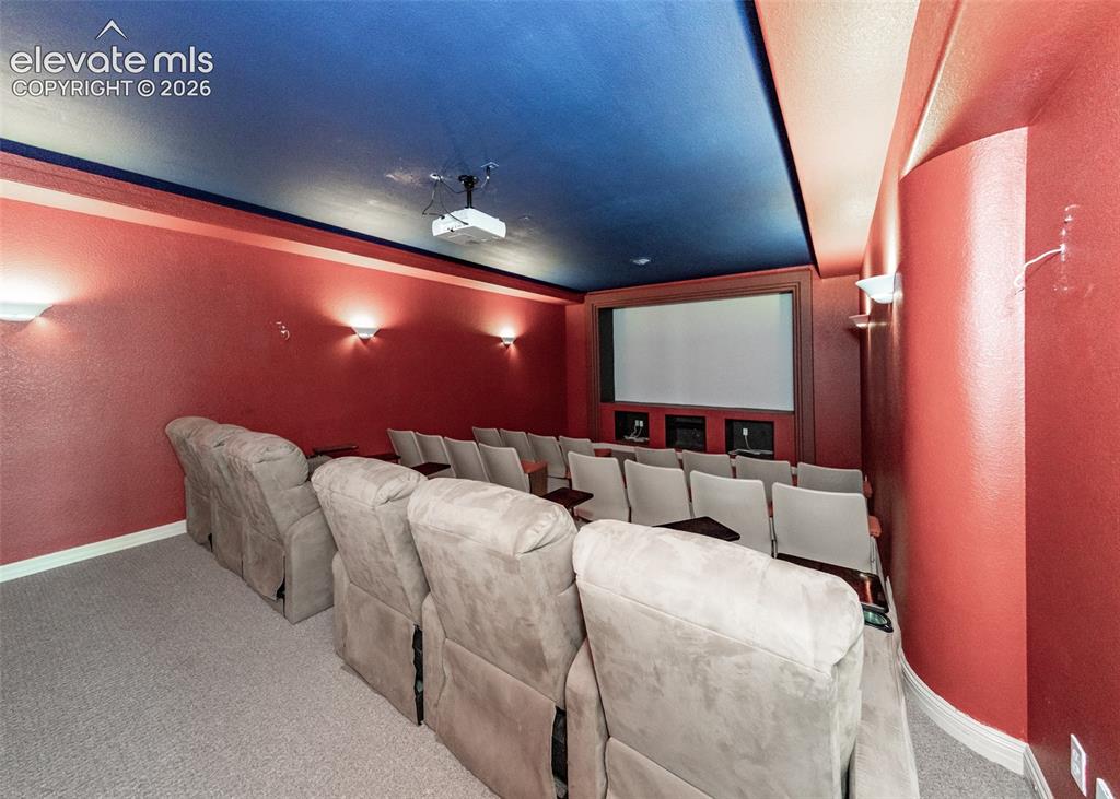 Image 36 of 50: Dedicated media room featuring a large projection screen, mounted projector