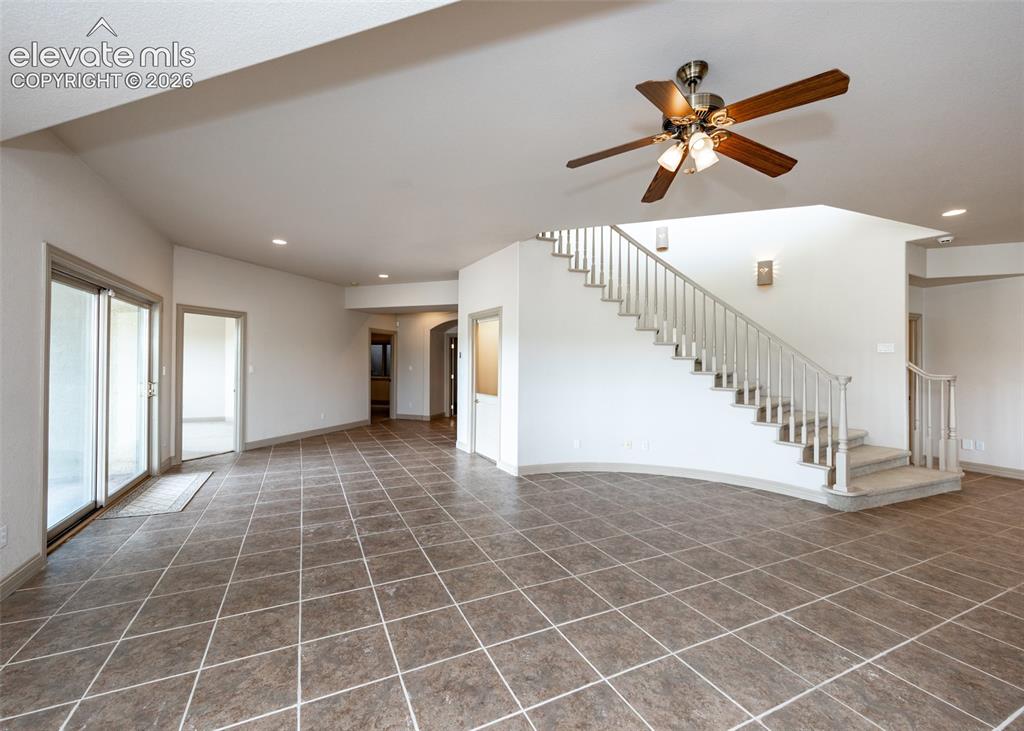 Image 38 of 50: Spacious living area featuring large format tile flooring, a curved stairca
