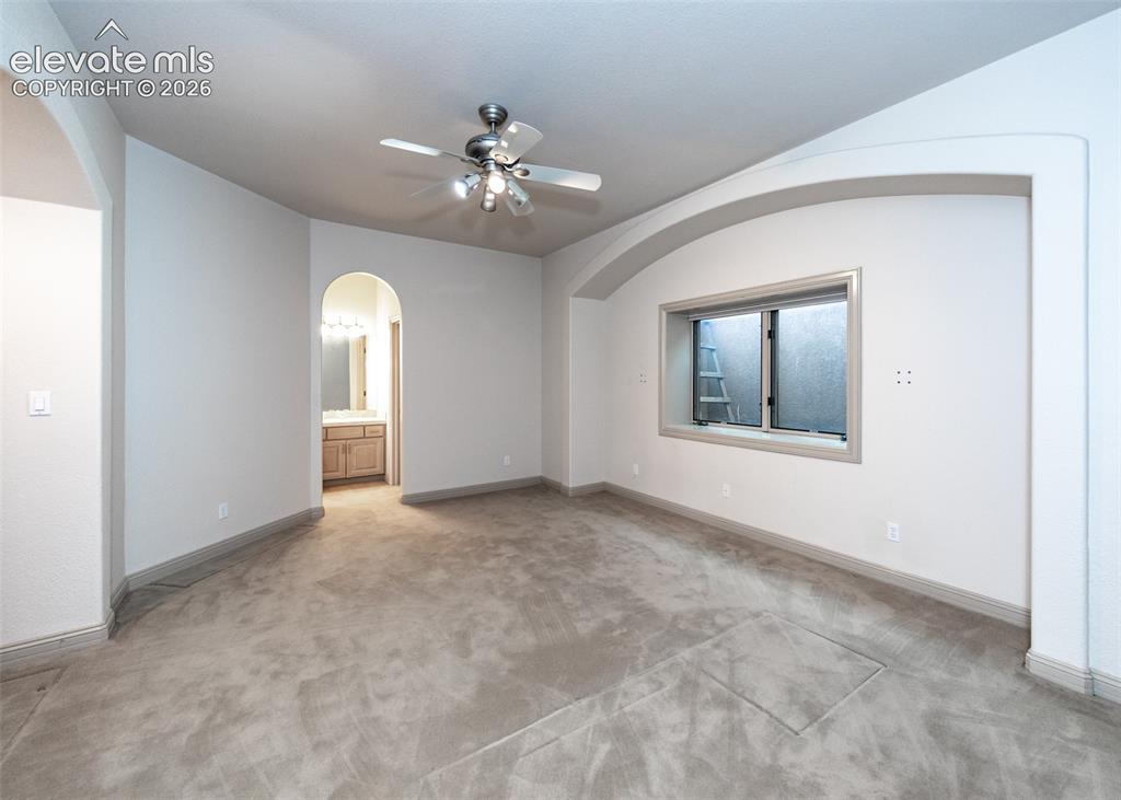 Image 39 of 50: Spacious room with plush carpet flooring and a ceiling fan with integrated