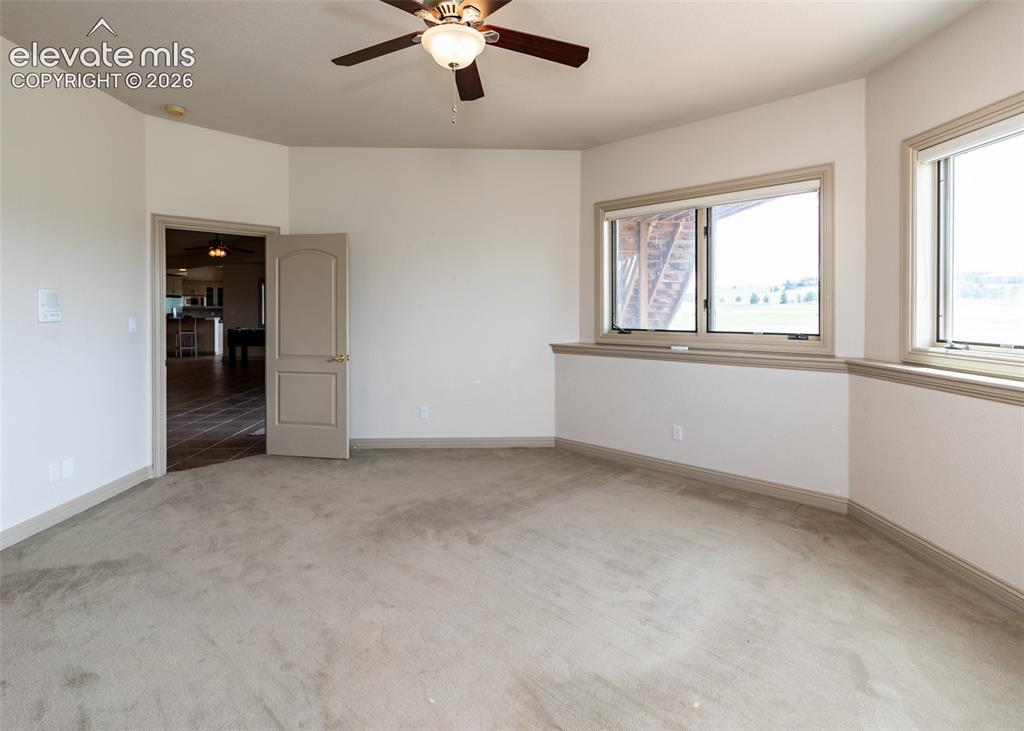 Image 40 of 50: Spacious room featuring neutral carpeting, a ceiling fan with integrated li