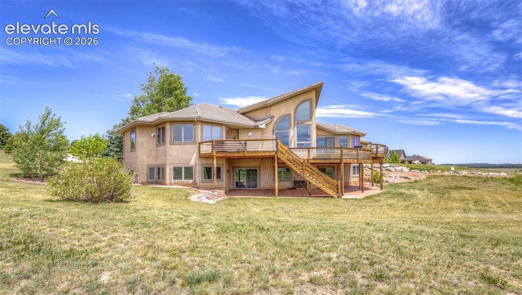 Image 44 of 50: Contemporary stucco exterior with a multi-level wood deck, abundant windows