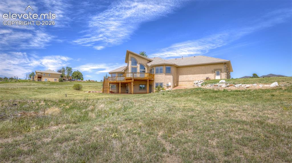 Image 45 of 50: Contemporary stucco residence featuring a multi-level deck, expansive windo