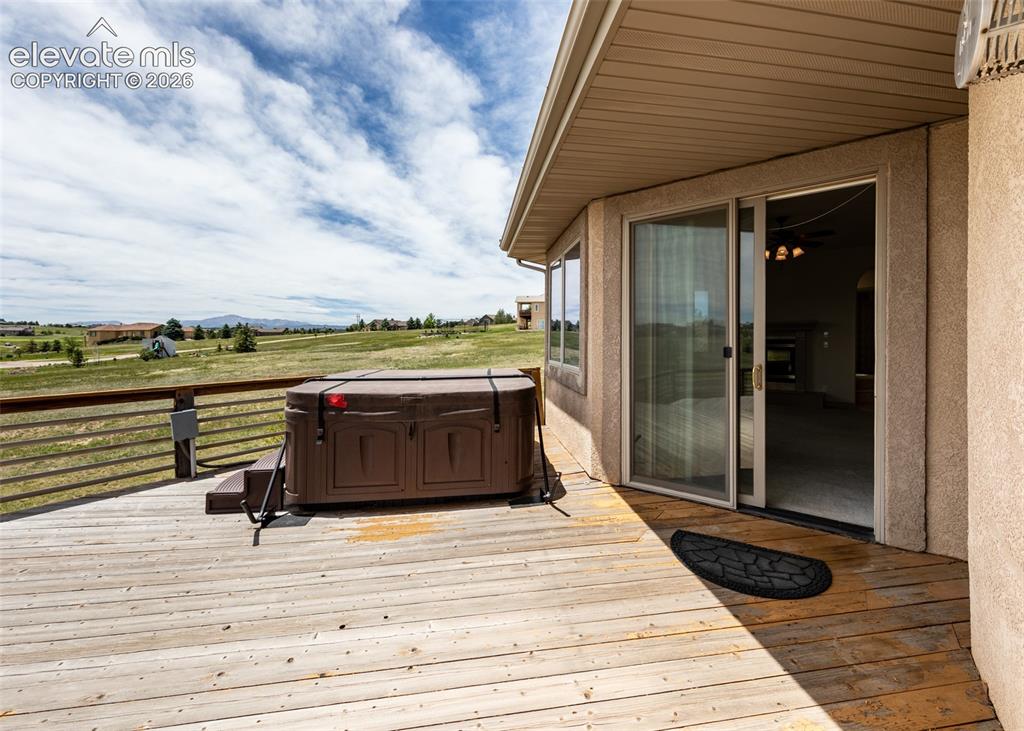 Image 46 of 50: Expansive wood deck featuring a built-in hot tub, durable railing, and a sl