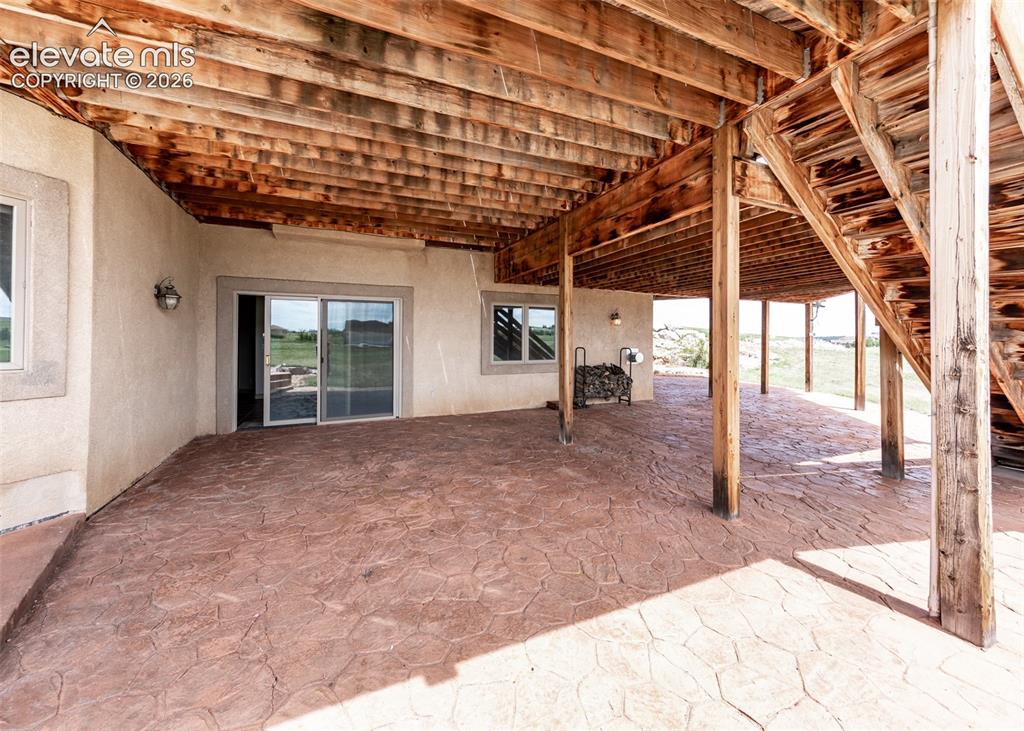 Image 48 of 50: Expansive covered patio featuring stamped concrete flooring, a natural wood