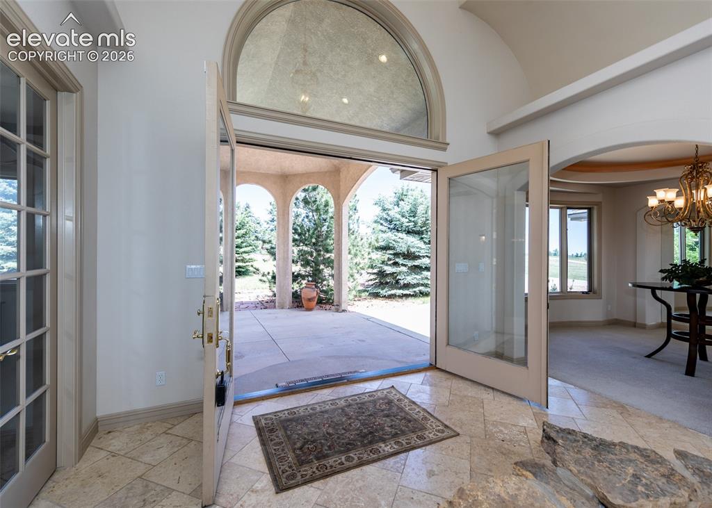 Image 7 of 50: Foyer entry featuring a large arched transom window, double glass-paneled d