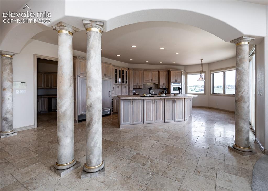 Image 9 of 50: Open-concept kitchen featuring light wood cabinetry, a central island with