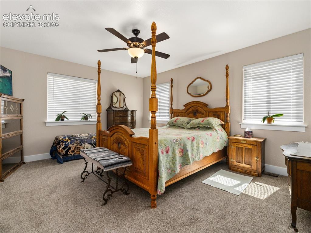 Image 16 of 21: Carpeted bedroom featuring two windows with blinds, a ceiling fan with inte
