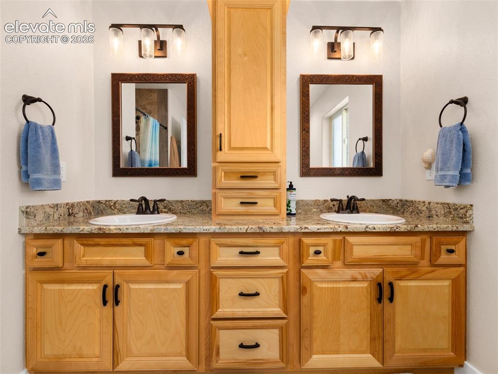 Image 20 of 21: Dual vanities with integrated white sinks and bronze-finish faucets
