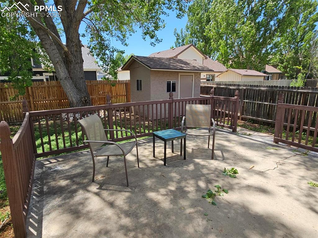 Image 24 of 27: Fenced backyard with patio