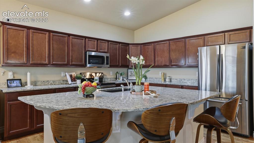 Image 17 of 50: The island kitchen boasts a pantry, dark wood cabinetry, granite countertop
