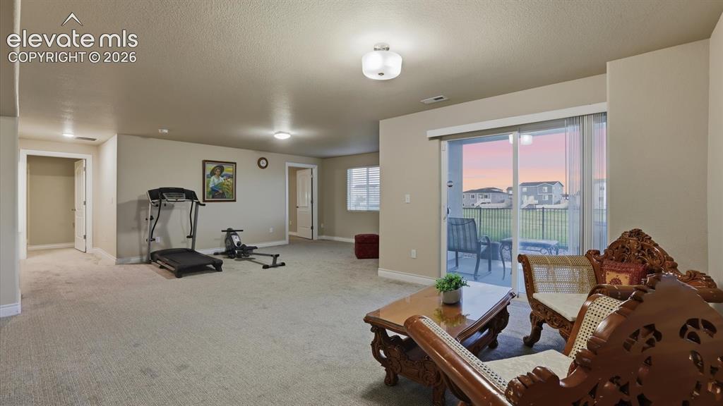 Image 41 of 50: Gym area of the Basement Family/Rec Room with slider to a covered patio.