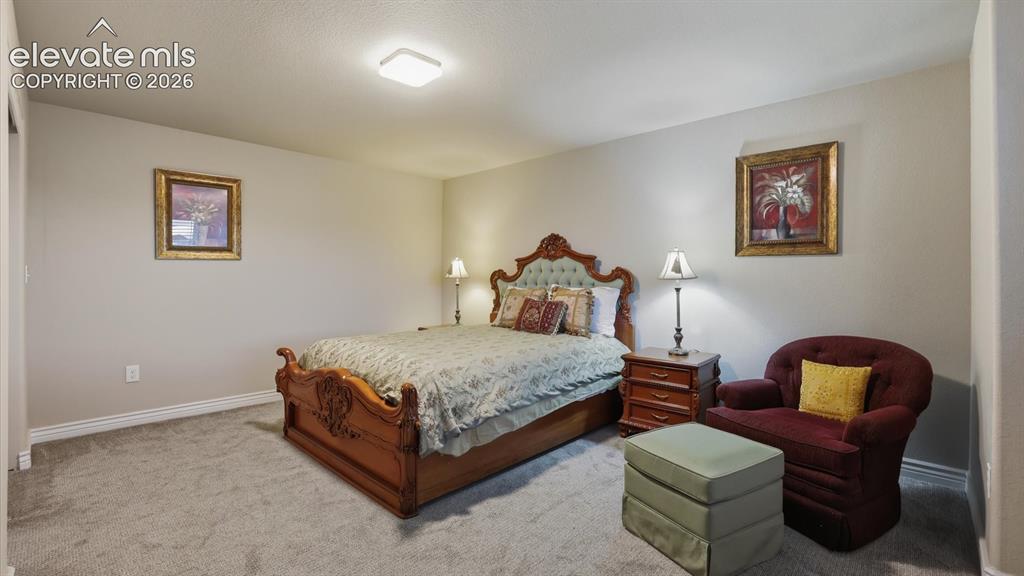 Image 47 of 50: Basement Bedroom #4 has neutral carpet and a sitting area.