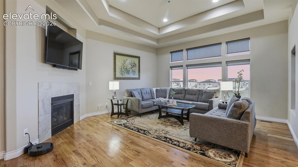 Image 5 of 50: The elegant Living Room features a tray ceiling, wall of windows, TV recess