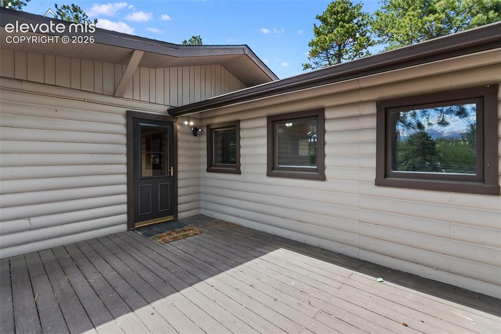 Image 11 of 36: Spacious wooden deck featuring light-colored horizontal siding and dark-fra