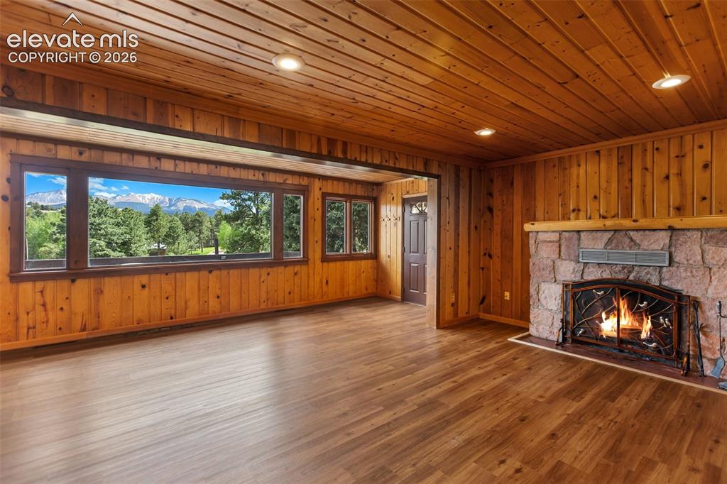Image 13 of 36: Expansive living area featuring a stone fireplace with a decorative metal s
