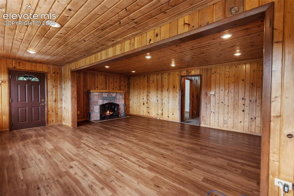 Image 14 of 36: Living area featuring plank wood-finish flooring, wood paneling on walls an