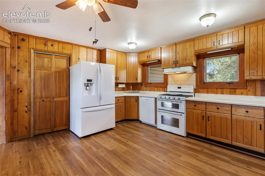 Image 18 of 36: Kitchen featuring wood-finish flooring, paneled walls, wood cabinetry, whit