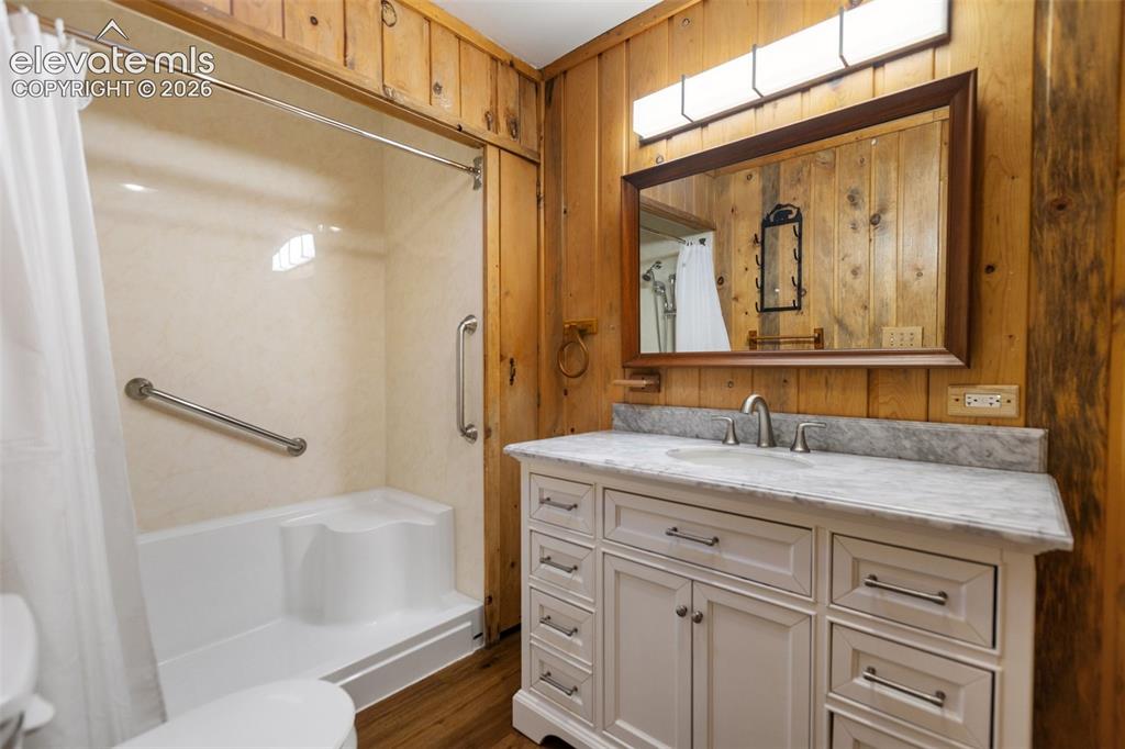 Image 20 of 36: Bathroom featuring wood-paneled walls and wood-finish flooring