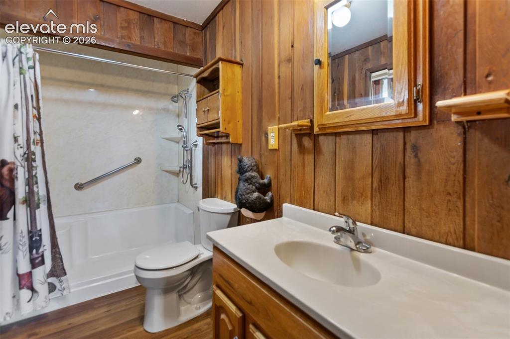 Image 21 of 36: Bathroom featuring wood-finish wall paneling, a white vanity with an integr
