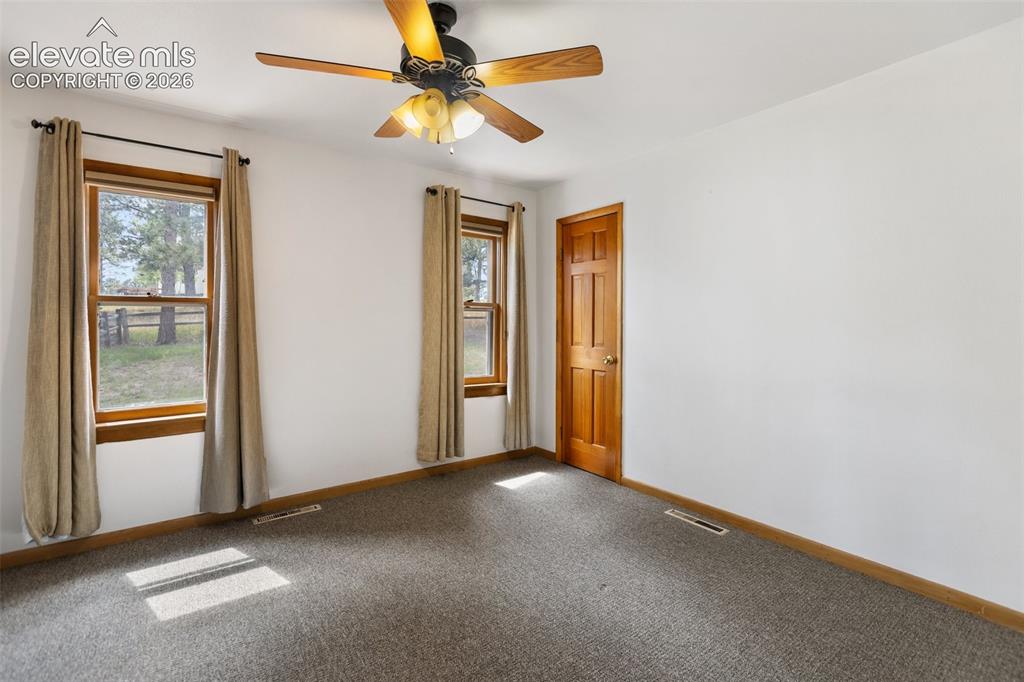 Image 22 of 36: Carpeted room featuring multiple windows with wood trim, a wood-panel door,