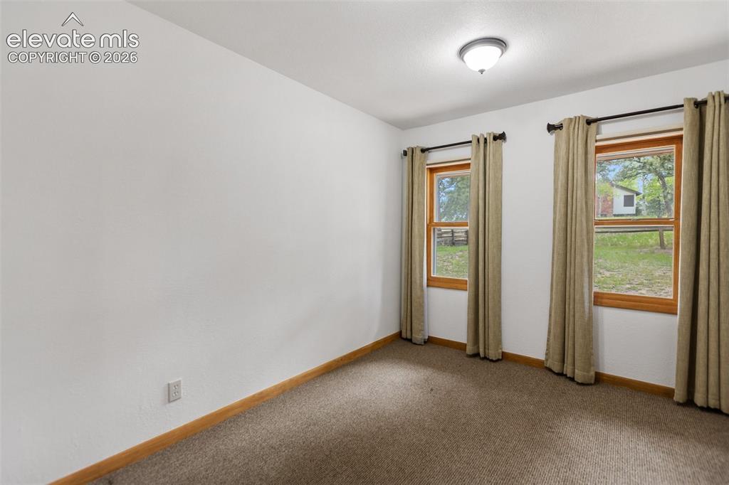 Image 24 of 36: Spacious room featuring two large windows with natural wood frames, neutral