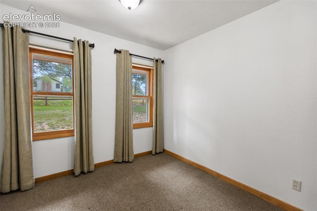Image 25 of 36: Carpeted room featuring two wood-framed windows, white walls, and a ceiling