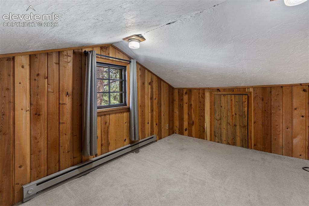 Image 31 of 36: Slanted ceiling room featuring natural wood paneling and a grid-pane window