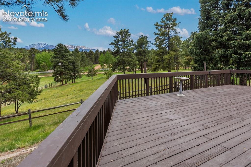 Image 33 of 36: Spacious outdoor deck with wood flooring and dark wood railing, overlooking