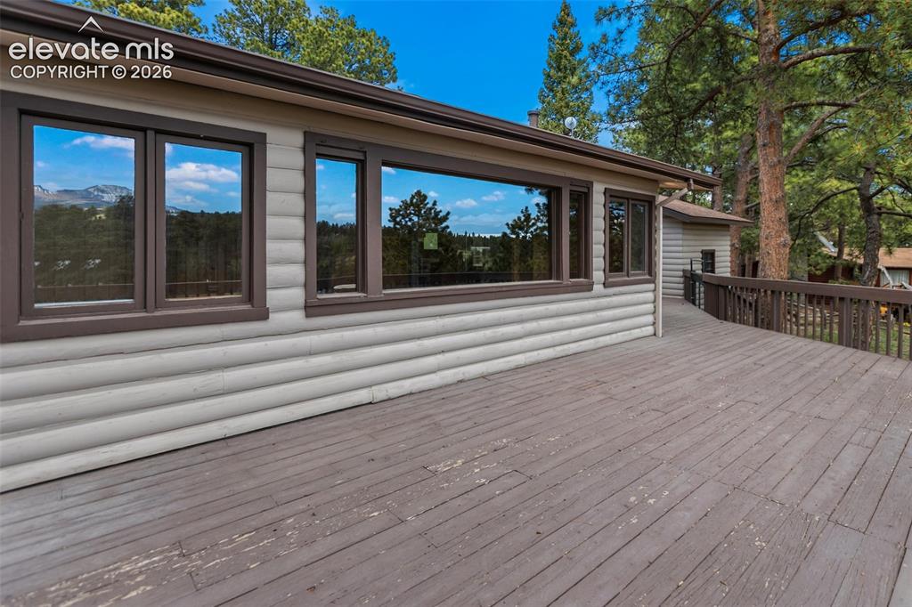 Image 34 of 36: Expansive exterior deck featuring a wooden railing and ramp