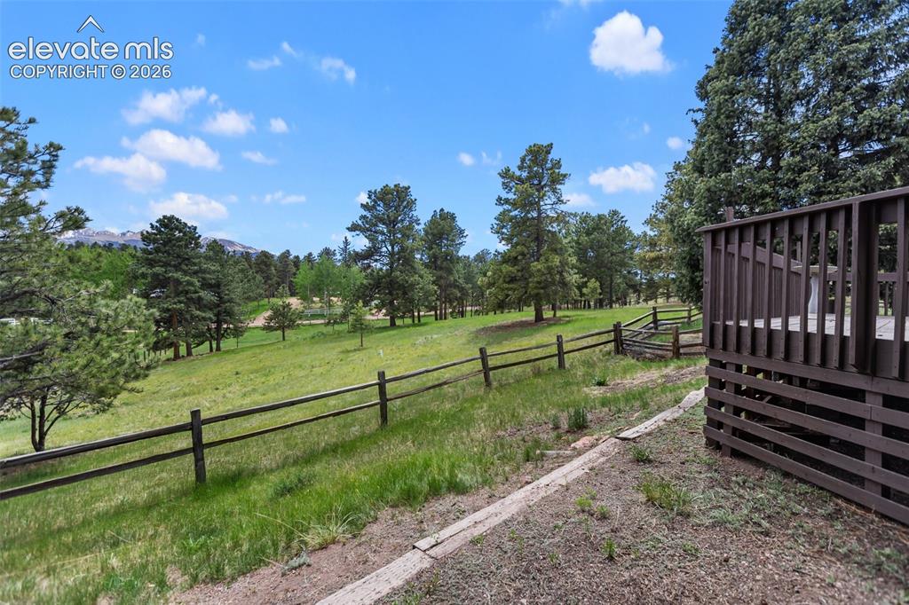 Image 6 of 36: Expansive outdoor deck with slatted railings overlooking a large grassy are