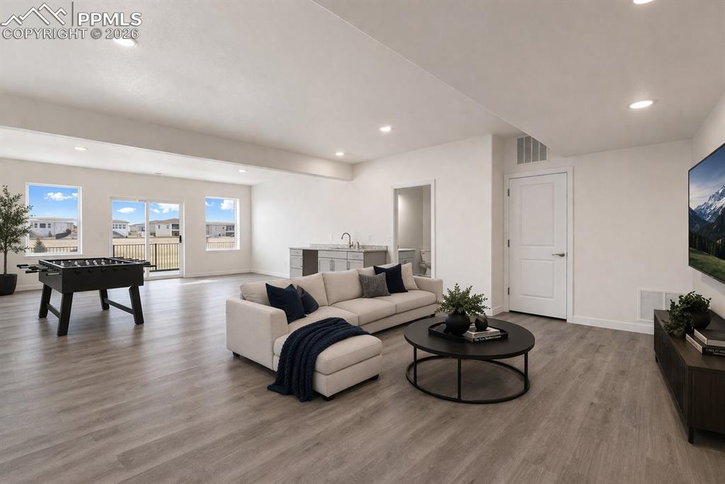 Image 6 of 46: Open basement space for games and lounging (virtual staging)