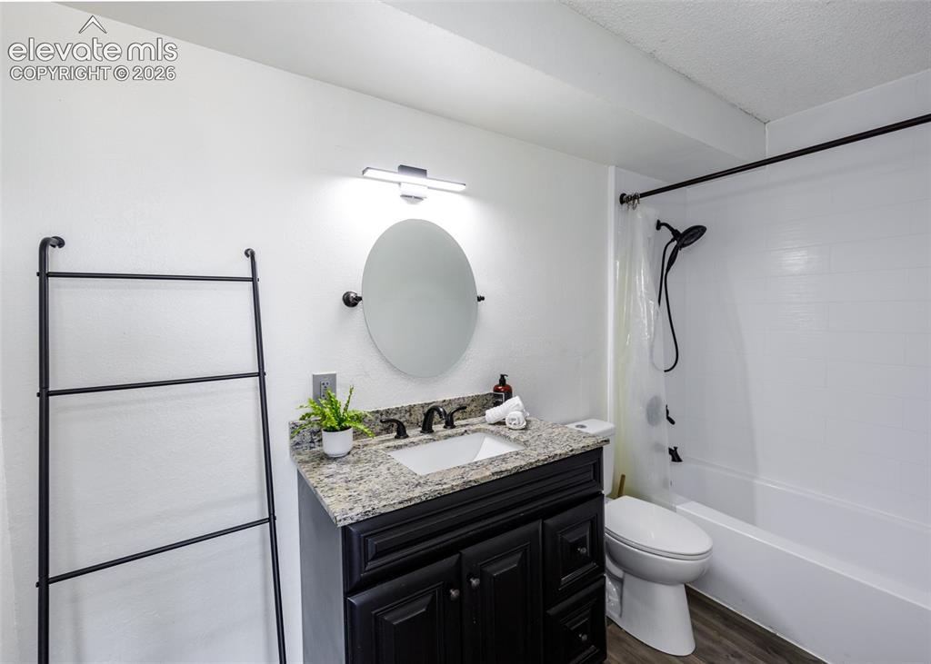 Image 10 of 12: Bathroom featuring a dark wood-finish vanity, light speckled countertop, an