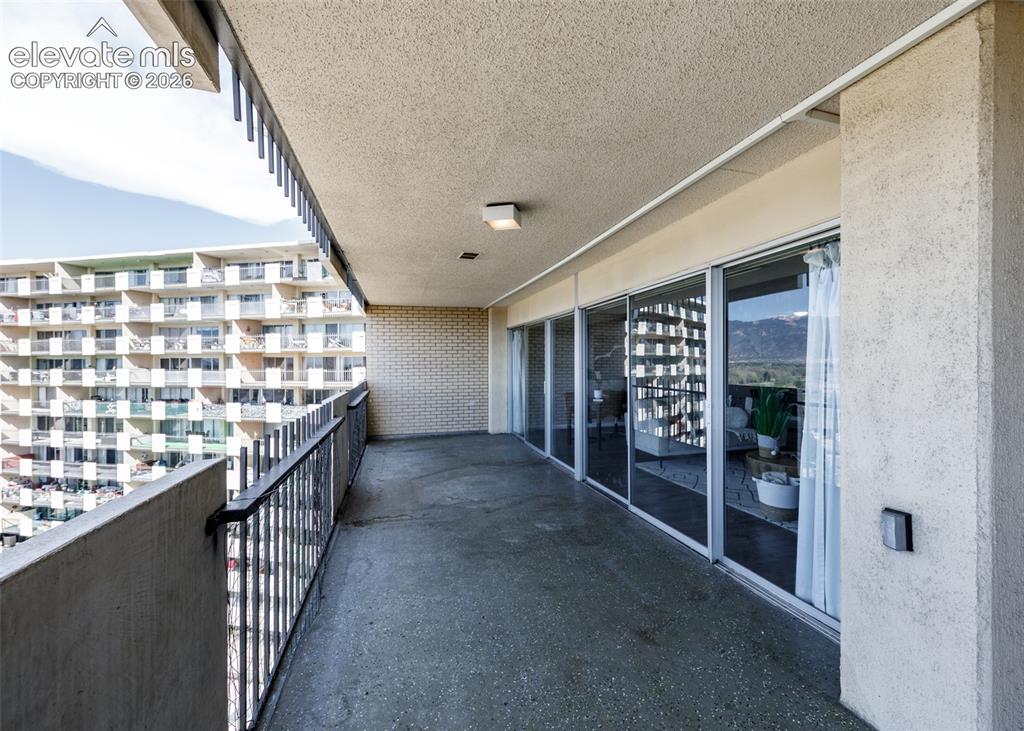 Image 11 of 12: Expansive balcony with concrete flooring, metal railings, and multiple slid